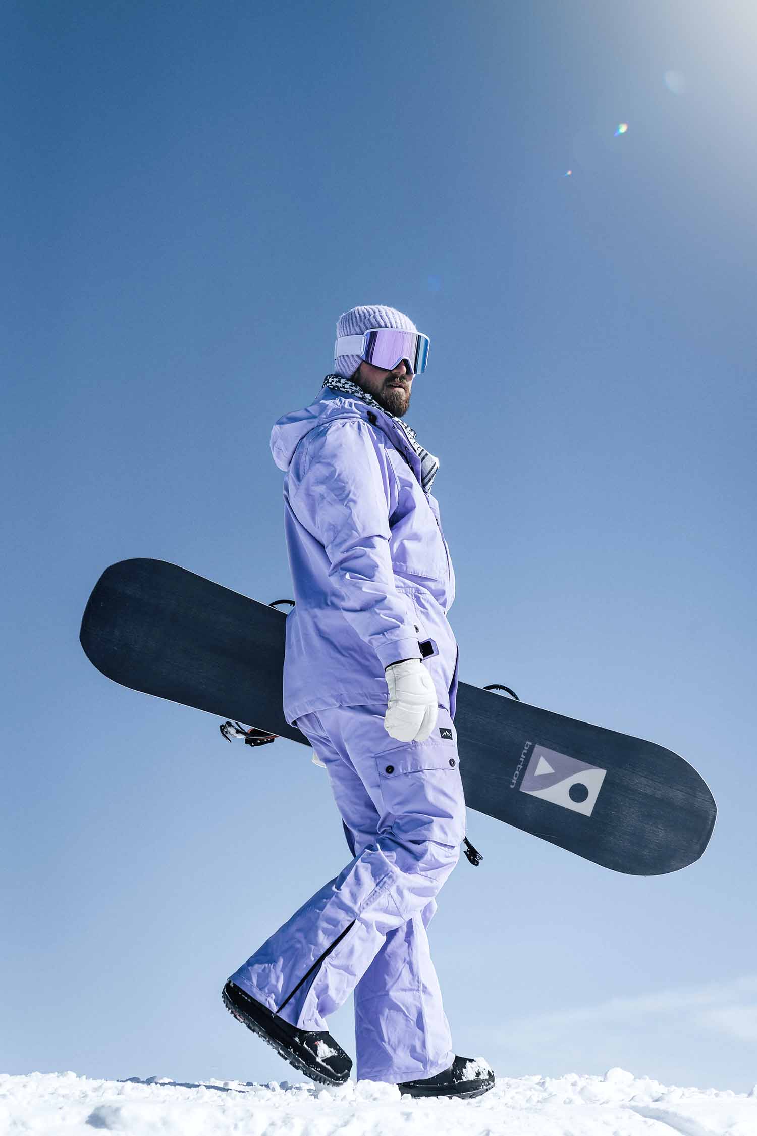 a person in a snow suit carrying a snowboard